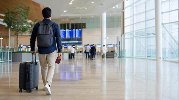 Expat walking through a Saudi airport departure hall with a suitcase and passport after getting a final exit visa