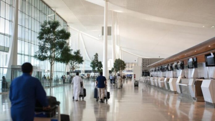 Jeddah airport Terminal 4 style departure hall with check-in counters and travellers with luggage trolleys